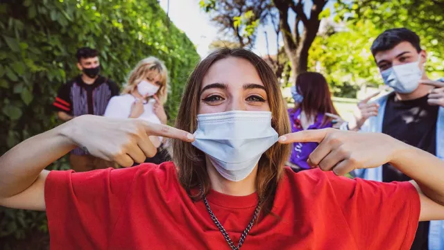 A girl points to a mask she's wearing